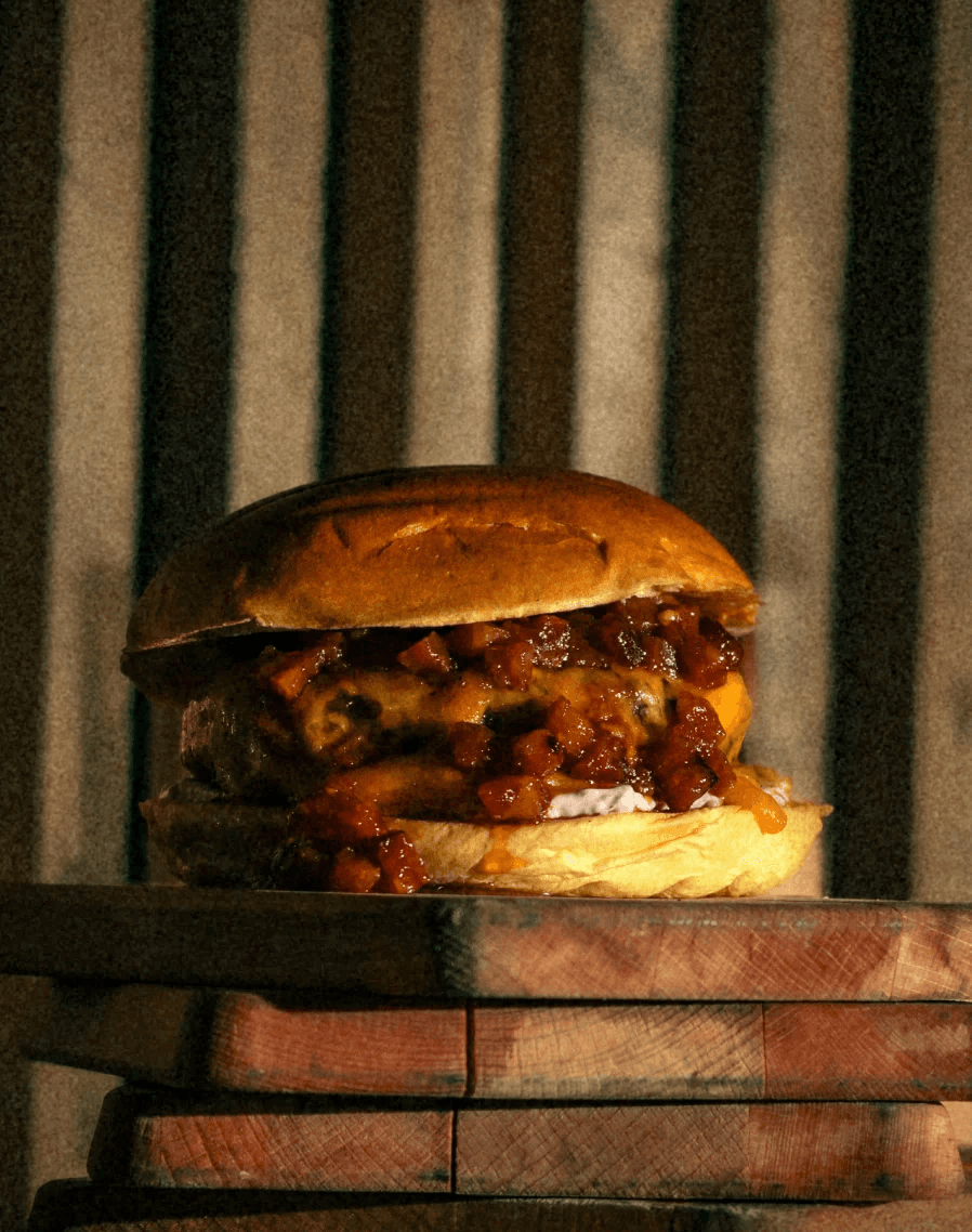 Jonnhy D. Pan Brioche con crema de queso de miel y nueces pecanas, además, queso cheddar americano, nuestra mermelada de Bacon macerado en barrica de ron Miel y BBQ.