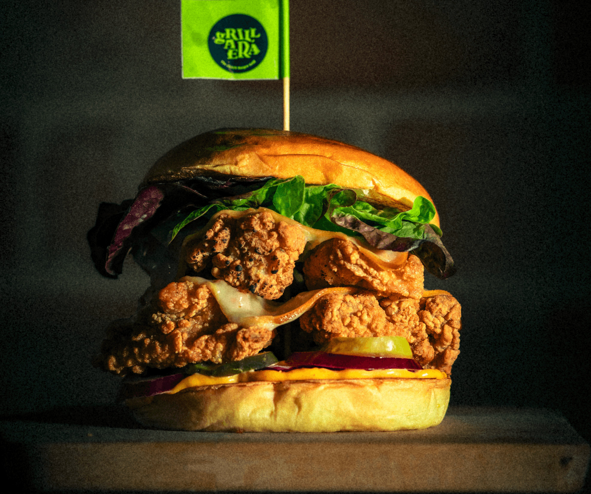 Big Lindsay. Pan Brioche con trozos de pollo crispy, queso cheddar blanco ahumado, queso cheddar salsa gromenaüer, pepinillos, cebolla morada y lechuga batavia.