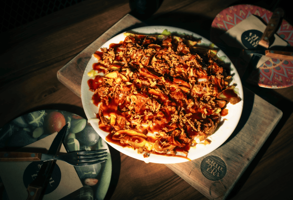 PapiPig. Patatas dipper con mozzarella y queso gouda fundidos, queso crema, pulled pork, salsa bbq bull eye - sweet whisky y topping de cebolla crispy.